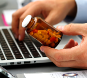 Person holding prescription bottle near a computer