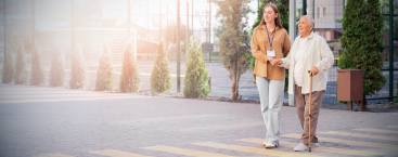 Healthcare worker walks with elderly patient